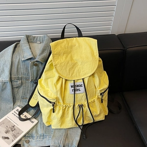 Close-up of bright yellow nylon backpack featuring drawstring closure and side pockets