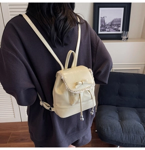 Détail du mini sac à dos blanc crème avec bordure en dentelle et nœud sur tissu gaufré