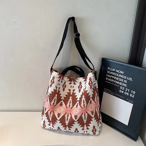 Detail of canvas tote bag showing brown geometric patterns and adjustable shoulder strap