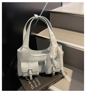 Vista dettagliata della borsa sottobraccio azzurra con tasche utility e nastro in pizzo