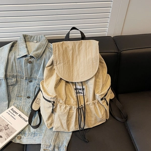 Detail view of a beige nylon backpack with drawstring closure and metal zippers