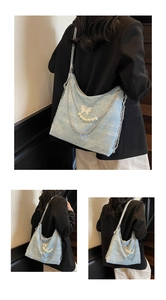 Detail of light blue hobo bag with pearls, metal chains, and butterfly charm accents