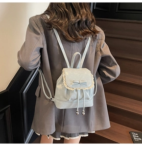 Détail du sac à dos en cuir verni bleu clair avec bordure en dentelle et noeud
