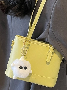 Chic light green bucket bag with plush charm, showing elegant crossbody carry style