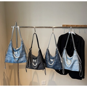 Detail view of denim hobo bags in four shades with pearl and butterfly chain accents