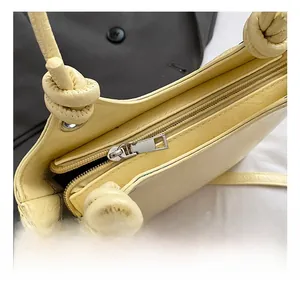 Close-up of premium metal zipper and decorative knotted strap on a yellow bucket bag