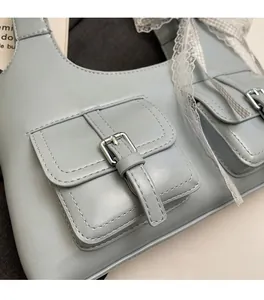 Dettaglio della borsa tote azzurra in PU con tasche a patta e fiocco in pizzo bianco