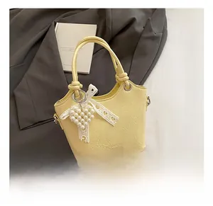 Detailed macro view of yellow bucket bag with pearl heart charm and lace bow decor