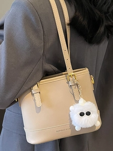Beige bucket bag for women with plush monster charm and adjustable shoulder strap