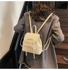 Détail du mini sac à dos crème avec dentelle, nœud et fermeture par cordon de serrage