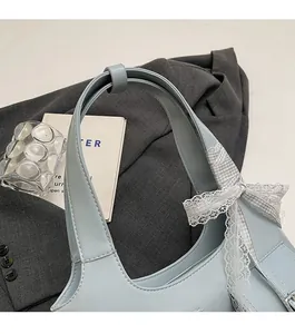 Dettaglio borsa sottobraccio azzurra con fiocco in pizzo decorativo e tracolla resistente