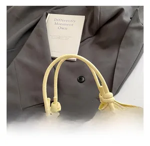Close-up of pale yellow bucket bag with textured leather and knotted handle detail