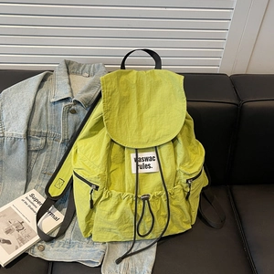 Detail of neon green nylon backpack showing drawstring closure and brand label