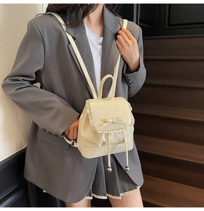 Vue détaillée du sac à dos blanc brillant avec bordure en dentelle et nœud décoratif