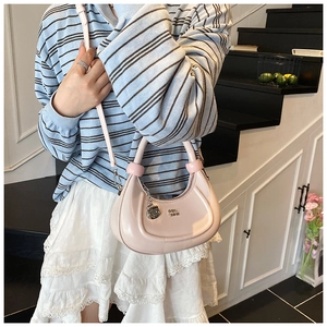 Detail of light pink crescent bag with silver logo and decorative metal chain strap