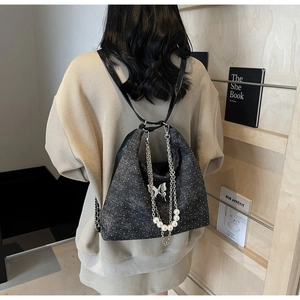 Detail view of glitter material tote bag with butterfly metal ornament and pearl chain