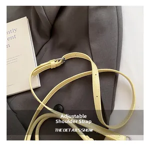 Detail of adjustable cream leather shoulder strap with metallic eyelets and buckle
