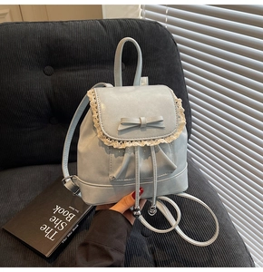 Détail d'un mini sac à dos bleu clair avec dentelle élégante et nœud sur un canapé doux