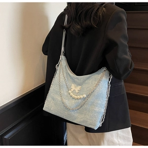 Detail of light blue glitter tote bag with silver chains, butterfly and pearls