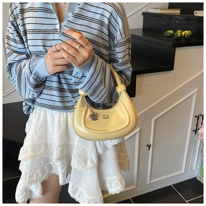 Detail of light yellow crescent hobo bag with unique knot handle design and metal logo