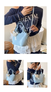Detail of light blue textured leather bucket bag with pearl lace heart charm and strap