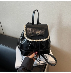 Détail du sac à dos noir brillant avec bordure en dentelle blanche, nœud et cordon perlé