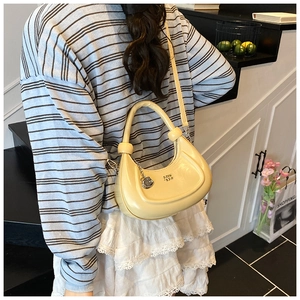Chic cream yellow crescent bag with knotted strap and owl charm shown on model