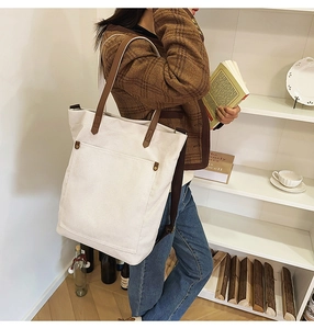 Detailed texture of beige canvas tote with brown leather strap and metal rivets