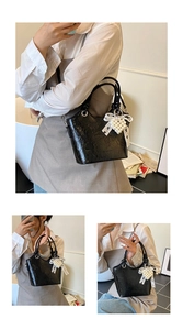 Detail of black glossy patent leather bucket bag with pearl heart and lace bow accent