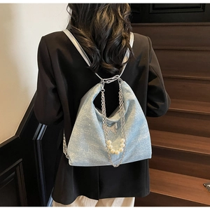 Detail of light blue sequined backpack with silver chains and pearls on a model