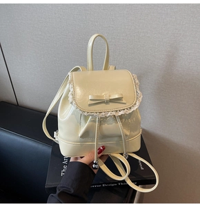 Détail du mini sac à dos en cuir verni beige avec dentelle et nœud élégant