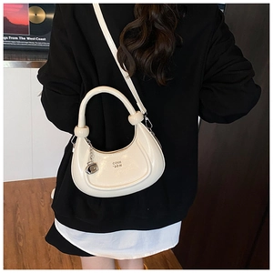 Detail of cream crescent bag with silver G pendant and embossed branding on model