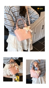 Close-up of sakura pink bucket bag featuring pearl heart charm and lace bow detail