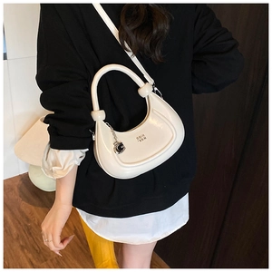 Detailed view of cream crescent bag featuring a decorative knot handle and metal G pendant