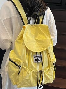 Bright yellow lightweight nylon drawstring backpack featuring a white logo label on model