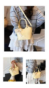 Detail view of yellow bucket bag with lace bow and pearl heart charm on stairs
