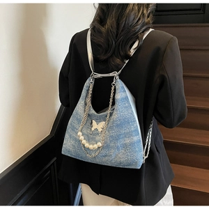 Macro detail of glitter blue tote bag featuring silver butterfly buckle and pearl chain strap
