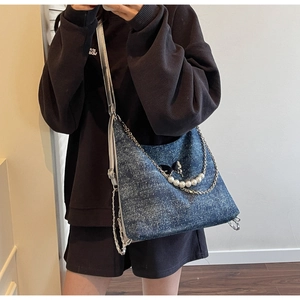 Close-up of washed denim tote with silver chain, pearl strap and black bow accessory