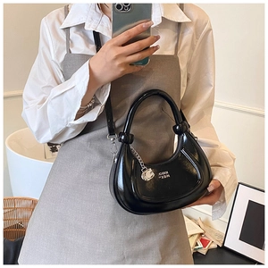 Detailed macro view of the glossy black crescent bag featuring silver chain decor and handle