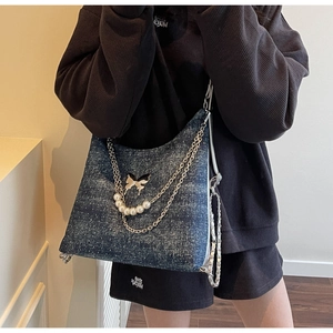 Detail of blue denim tote bag with butterfly pattern, pearl charms and silver chain