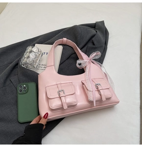 Dettaglio della borsa rosa con tasche, fibbie in metallo e fiocco decorativo in pizzo