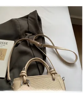 Detailed close-up of beige woven bucket bag with silver hardware and adjustable strap