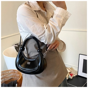 Detail of black glossy crescent bag with silver hardware and metallic letter decoration