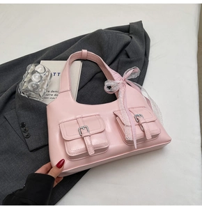 Dettaglio della borsa rosa con tasche a fibbia e fiocco Y2K su giacca grigia