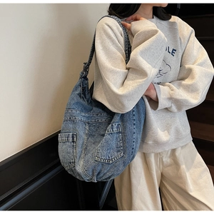 Detail of blue denim tote bag with vintage wash and functional multi-pocket design