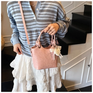 Detail of pink bucket bag with knotted handle and elegant pearl heart pendant