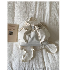 Detalle de la mochila de lona blanco crema con cierre de cordón y cremallera metálica