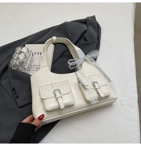 Dettaglio della borsa tote bianco sporco con doppie tasche e fiocco in pizzo a quadri grigi