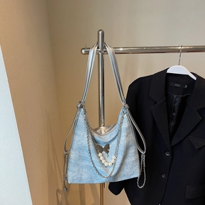 Close-up of light blue tweed tote bag with silver butterfly pendant and pearl chain