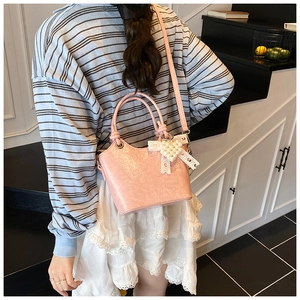 Pink pleated patent leather bucket bag with pearl heart pendant shown on model